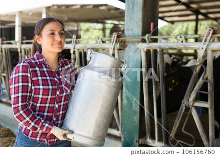 Female farmer carrying milk churn at dairy farm 106156760