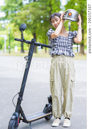 A young and cute woman wearing a helmet for traffic safety when driving an electric kickboard | Electric kickboard image A young and cute woman wearing a helmet for traffic safety when driving an electric kickboard | Electric kickboard image 106157167