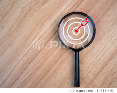 Magnifying glass with target icon placed on wooden table background. Business concept. Management concept. Business planning concept. business goal setting concept Magnifying glass with target icon placed on wooden table background. Business concept. Management concept. Business planning concept. business goal setting concept 106158060