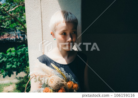 A woman sitting by the window with dried flowers 106159116