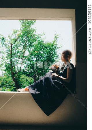 A woman sitting by the window with dried flowers A woman sitting by the window with dried flowers 106159121