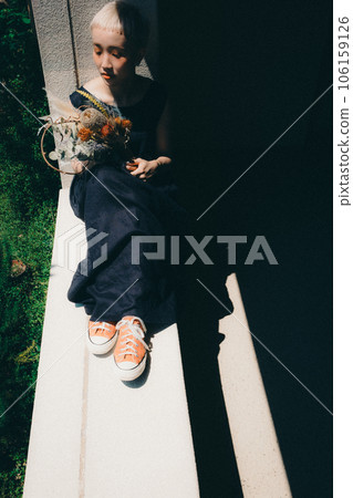 A woman sitting by the window with dried flowers 106159126