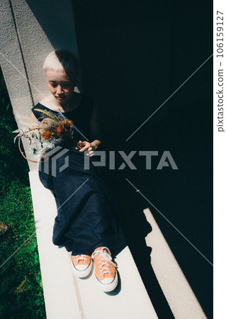 A woman sitting by the window with dried flowers 106159127