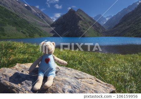 cute teddy bear traveler tourist resting by lake in mountains in summer in nature. Koksai Ainakol Lake in Tien Shan Mountains in Asia in Kazakhstan 106159956