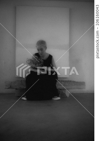 Black and white photo of a young woman standing indoors 106160043