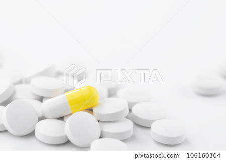Yellow and white pharmaceutical medical pills, capsules, tablets on a white table. Concept of medicine and healthcare. Yellow and white pharmaceutical medical pills, capsules, tablets on a white table. Concept of medicine and healthcare. 106160304