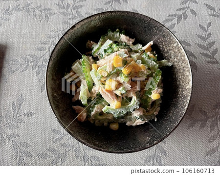 Bitter melon in a salad with tuna, corn and a litter peper with mayonnaise in black bowl on table. Top view. Bitter melon in a salad with tuna, corn and a litter peper with mayonnaise in black bowl on table. Top view. 106160713