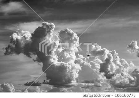 Cumulonimbus clouds rising in the summer sky and airplanes flying around b-6 high contrast monochrome Cumulonimbus clouds rising in the summer sky and airplanes flying around b-6 high contrast monochrome 106160775