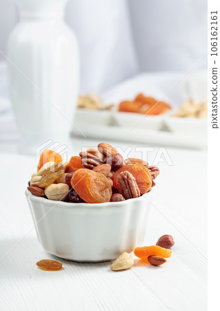 Dried fruits and assorted nuts on a white table. 106162161