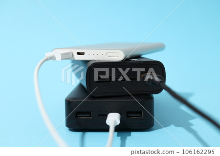 Powerbanks with cords on blue background, close up 106162295
