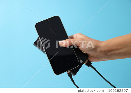 Powerbank and smartphone in hand on blue background Powerbank and smartphone in hand on blue background 106162297