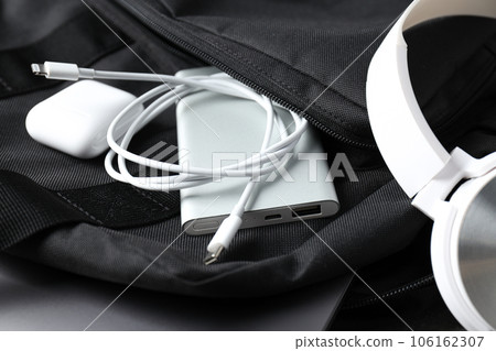Powerbank and wireless headphones in backpack pocket on white background, close up Powerbank and wireless headphones in backpack pocket on white background, close up 106162307