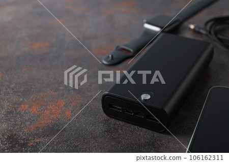 Powerbank and smart clock on dark gray background, close up 106162311