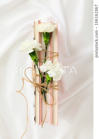 Books and flowers tied with twine on white background, top view Books and flowers tied with twine on white background, top view 106162867