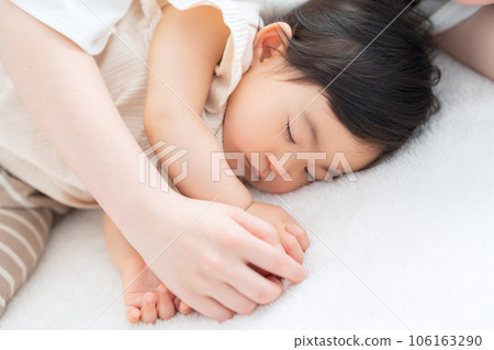 Baby and young mother taking a nap in the living room 106163290