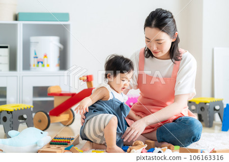 Young nursery teacher playing with baby in nursery 106163316