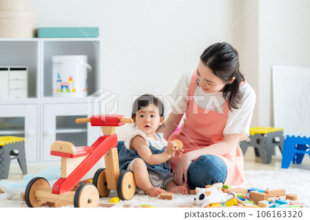 Young nursery teacher playing with baby in nursery 106163320