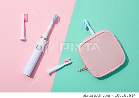 Electric toothbrushes and case on pink and green background, top view 106163614