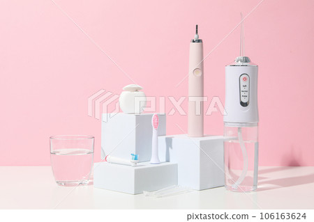 Electric toothbrush, irrigator and glass of water on pink background Electric toothbrush, irrigator and glass of water on pink background 106163624