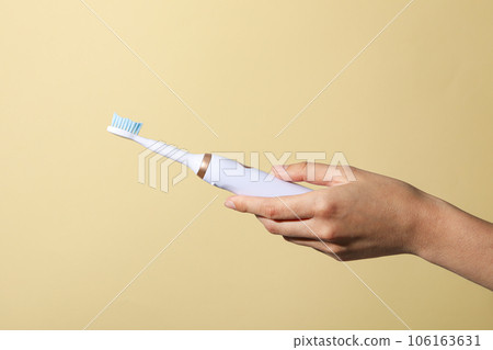 Electric toothbrush in female hand on beige background 106163631