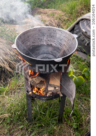Cooking food or pilaf in a cauldron on fire. Cooking in cauldron on open fire in nature. Bowler on bonfire in forest. Close-up fire flame. Copy space. 106164054
