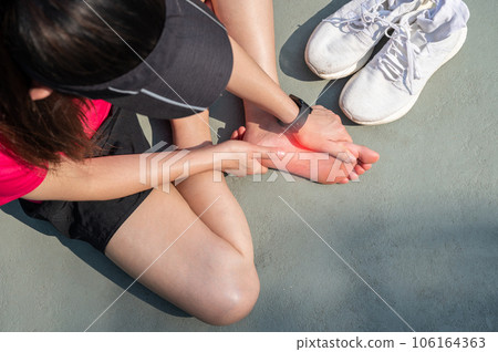 Top view of runner woman suffering from injury and she trying to do foot massage by herself. A foot massage used to decrease pain, relieve tension and improve circulation. 106164363