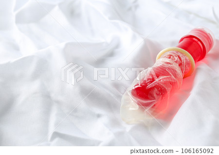 Condom on a red bottle with lubricant on a white background, place for text 106165092