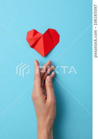 Red paper heart with a hand on a blue background. Blood donation Red paper heart with a hand on a blue background. Blood donation 106165097