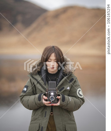 A woman holding a twin-lens reflex camera near Kusasenri Pond 106165294