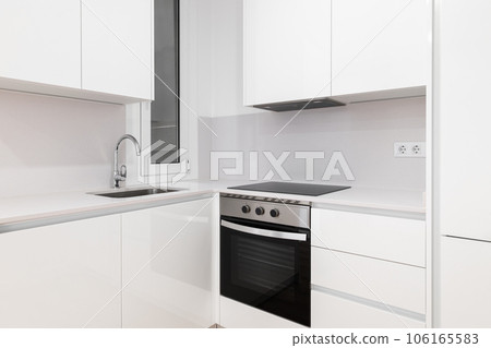Modern kitchen with sleek white cabinets and a stylish black stove top oven Modern kitchen with sleek white cabinets and a stylish black stove top oven 106165583