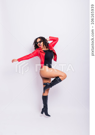 African American curvy female in black bodysuit and jacket on red and white background in studio 106165939