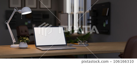 A wooden desk with a laptop in a modern room at night. Workspace at night concept. 106166310