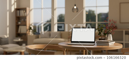 A laptop white screen mockup on a wooden table in a cozy, contemporary living room. A laptop white screen mockup on a wooden table in a cozy, contemporary living room. 106166320