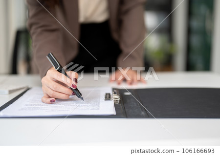 Close-up image of a businesswoman reading documents or a contract, signing contract 106166693