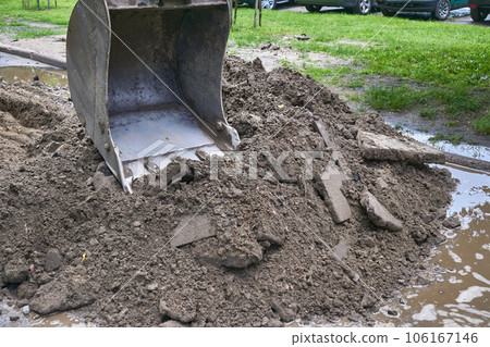 Excavator bucket picking up the ground, soil on road repair Excavator bucket picking up the ground, soil on road repair 106167146