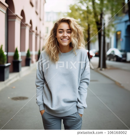 Beautiful young lady dressed in gray sweater, commercial sweatshirt mock-up, smiling blonde woman standing in the street 106168002