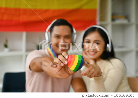 Male and female hands holding rainbow heart to camera. LGBTQ, human rights and equality social 106169105