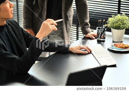 Shot of young male economist working on investment and marketing projects with colleague in office Shot of young male economist working on investment and marketing projects with colleague in office 106169109