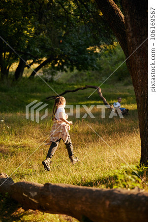 Little active child, girl in casual clothes running, playing in meadow in forest on warm sunny day Little active child, girl in casual clothes running, playing in meadow in forest on warm sunny day 106169567