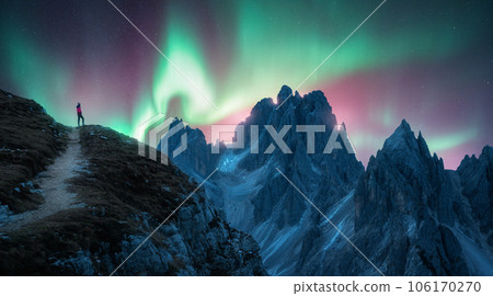Northern lights and young woman on mountain peak at night 106170270