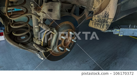 Car disc brake system. Car suspension in process of new tire replacement at garage workshop. Car disc brake mechanic check and repair. Disk break rotor. Car in change tire process at service station. 106170372