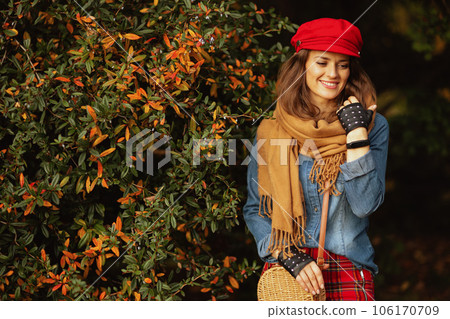 pensive modern woman in jeans shirt and red hat with scarf 106170709