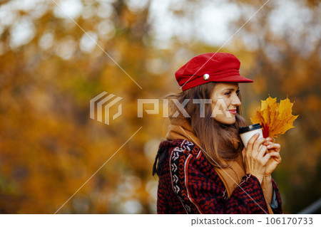 pensive young 40 years old woman in red hat with autumn leafs 106170733