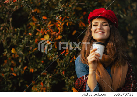 smiling young woman in red hat with autumn leafs and scarf smiling young woman in red hat with autumn leafs and scarf 106170735