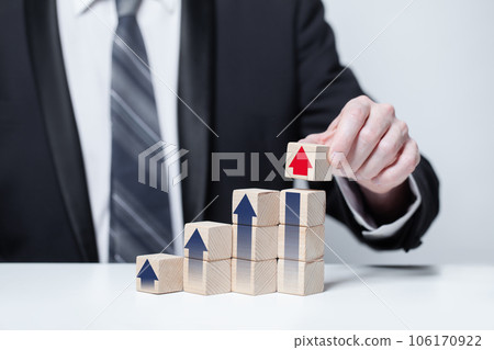 Wooden blocks with black and red arrows icons, hand in suit holding cube 106170922