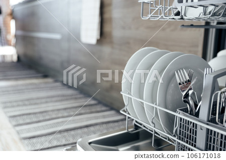 Opened dishwasher machine at kitchen with clean utensil, white plates Opened dishwasher machine at kitchen with clean utensil, white plates 106171018