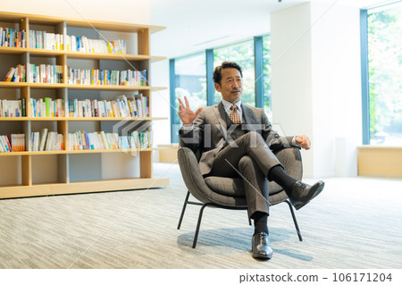 A man in a suit sitting on a chair and talking 106171204