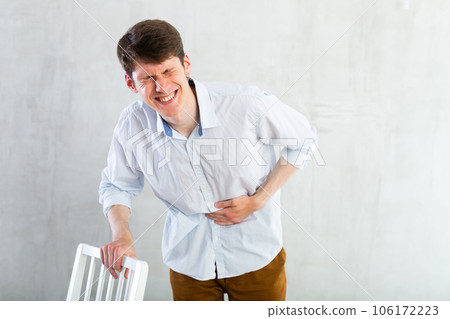 Young guy holding on to his sore stomach Young guy holding on to his sore stomach 106172223