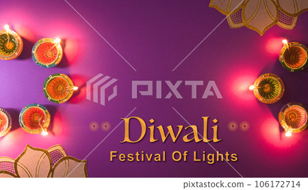 Happy Diwali - Clay Diya lamps lit during Dipavali, Hindu festival of lights celebration. Colorful traditional oil lamp diya on purple background 106172714