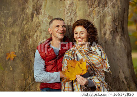 smiling stylish couple in park with autumn leafs near tree 106172920
